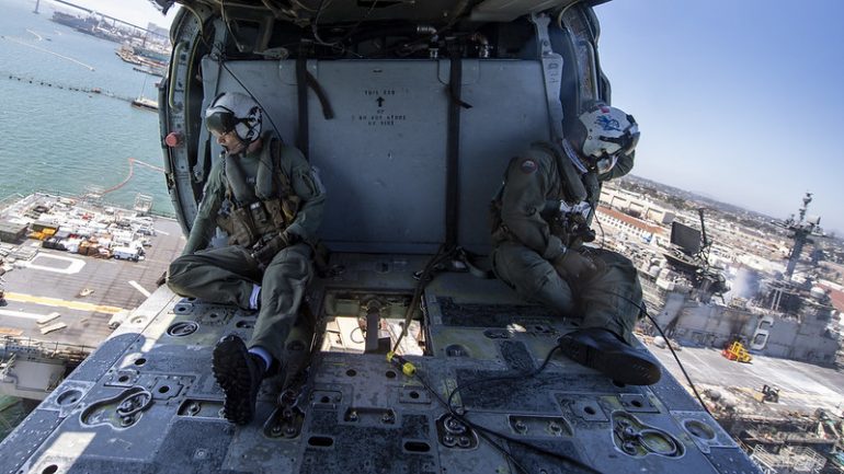 Tripulantes dum helicóptero naval SH-60 Seahawk, empregue no combate ao incendio observam o estado de destruição das superestruturas e do convés de voo do USS BONHOMME RICHARD LHD-6 (imagem US Navy)